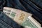 Folded Ukrainian hryvnia and American dollars protrude from the pocket of jeans close-up.