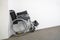 folded wheelchair at a white wall