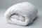 Folded white duvet on bed for winter season, household chores, and hotel or home textile