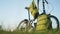 Folding bicycle stands in the park at sunset. On it hang green backpacks