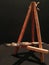 Folding easel tripod and painting brushes on black background.