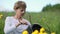 Folk crafts. Handmade. Young woman weaves rattar baskets sitting in the grass. Yellow flowers in the foreground