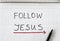 Follow Jesus Christ, handwritten text message with a red arrow showing a way written on a spiral notebook