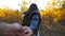 Follow me shot of young woman pulls her boyfriend along trail through small oak trees. Happy girl holds male hand and