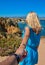 Follow me there. Blonde girl in blue dress holds the man`s hand and indicate a beautiful sea to relax