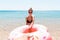 Follow me Vacation concept. girlcalls to swim in the sea and waves her hand. Girl relaxing on inflatable ring in the sea. Summer