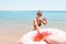 Follow me Vacation concept. woman calls to swim in the sea and waves her hand. Girl relaxing on inflatable ring in the sea. Summer