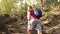 Follow shot of male hiking on stone trail in green forest with sun flares, tracking shot from behind. Outdoor activities