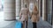 Follow shot of mature tourist couple carrying suitcase walking outdoors.