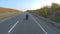 Follow to biker riding on modern sport motorbike at autumn highway. Motorcyclist racing his motorcycle on country road