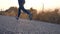 Follow to feet of young girl running at country road. Female leg jogging in nature. Sporty active lifestyle. Slow motion