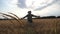 Follow to happy young agronomist raising hands while running through wheat field. Unrecognizable farmer having fun