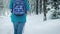 FOLLOW Young female hiking with a backpack in beautiful winter forest. uses sticks for Nordic walking.