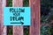 Follow Your Dreams inspirational life quote text written on paper on a fence