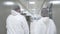 following back shot of two factory workers walking through pharmaceutical plant hall