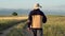 Following an elderly hiker with trekking pole walking in countryside, in summer afternoon.