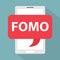 FOMO fear of missing out wriiten in speech bubble on smartphone