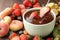 Fondue forks with strawberries in bowl of melted chocolate surrounded by other fruits on table