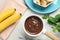 Fondue pot with milk  and bananas on light table, top view