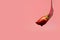 Fondue strawberry soaked in hot black chocolate on a fork with pink background with minimalist style