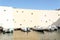 Fontage of a beige building with blue sky and boats