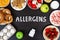 Food allergens as milk, oranges, tomatoes, garlic, shrimp, peanuts, eggs, apples, bread, strawberries on wooden table