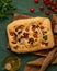 Food art. Focaccia, Flatbread with tomatoes,on dark green linen textile tablecloth. Top view