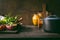 Food background with cast iron cooking pot, fresh seasoning and spices on rustic kitchen table. Copy space. Healthy eating, clean