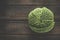 Food background with close up of whole raw green savoy cabbage at rustic wooden kitchen table. Healthy garden vegetable. Top view