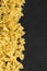 Food background - dry farfalle pasta on black background, whole wheat uncooked ingredient