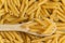 Food background - dry penne pasta and wooden spoon, whole wheat food ingredient