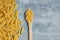 Food background - dry penne pasta and wooden spoon, whole wheat uncooked ingredient