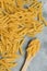 Food background - dry penne pasta and wooden spoon, whole wheat uncooked ingredient