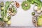 Food background with green vegetables in bowls on light table with knife: green peas, kohlrabi, lettuce, zucchini, cucumber, green