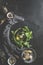 Food background with parsley, olive oil, round black cutting board, spices, dish cloth and kitchen utensils on dark kitchen table