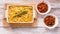 Food banner. Baked fettuccine with cheese and smoked sausage in a ceramic bowl and mussels in tomato sauce on a wooden table.