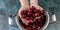 Food banner. Children`s hands hold ripe sweet cherry. Sweet cherry in a pan on a blue concrete background