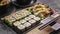 Food banner: tasty traditional Asian food. Vegetable sushi maki rolls, gyoza dumplings with salad on a black stone board. Bamboo