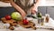 Food banner. A young chef in a brown apron uses a kitchen knife to cut vegetables for a delicious vegetarian salad. Cooking