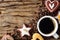 Food and beverage background of a cup of hot black coffee and assortment of cookies and roasted coffee beans on wooden plank