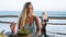 Food blogger woman films video about green salad bowl, dieting for fit skinny body at cafe, sea view. Travel influencer