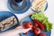 Food in blue designer dishes on light background. Women`s hand holding tomato.