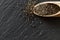 Food chia seeds in wooden spoon. Healthy pile flax superfood on black background. Salvia hispanica antioxidant grains on