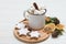Food composition with white mug with hot chocolate, cinnamon stick and marshmallows on a round wooden board with baked gingerbread