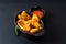 Food concept homemade organic Seasoned Baked Potato wedges in black bowl on black slate stone plate with copy space