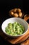 Food concept Spot focus Homemade creamy pesto gnocchi on black background with copy space