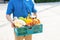 Food Deliver Asian man in blue uniform give fruit and vegetable to receiver customer front house