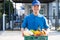 Food Deliver Asian man in blue uniform give fruit and vegetable to receiver customer front house