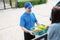 Food Deliver Asian man wearing mask in uniform give fruit and vegetable to receiver customer front house