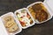 Food delivery. Bread, salad and pljeskavica - grilled dish of minced meat,  french fries in takeaway containers on rustic wooden